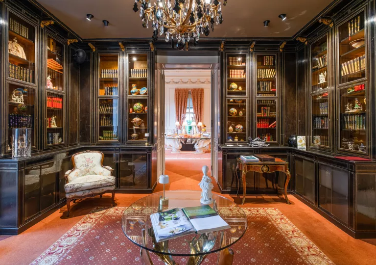 Library with large, wooden and marble shelves and cushioned chairs