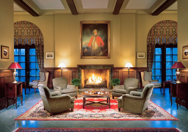 Hotel lobby, with cushioned chairs in front of a lit fireplace