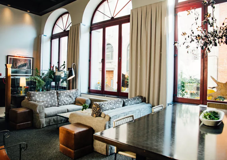 Seating and lounge area with large windows and tall curtains