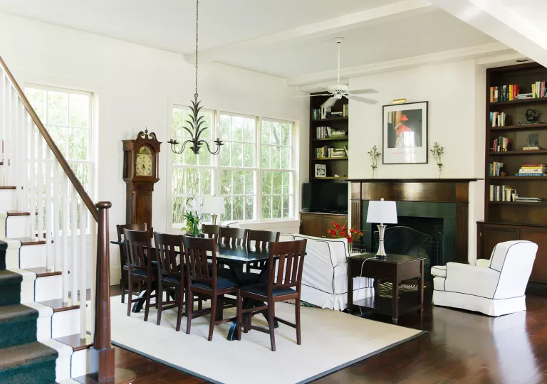 Living room with a wooden dining table over a white rug, and a fireplace to the right
