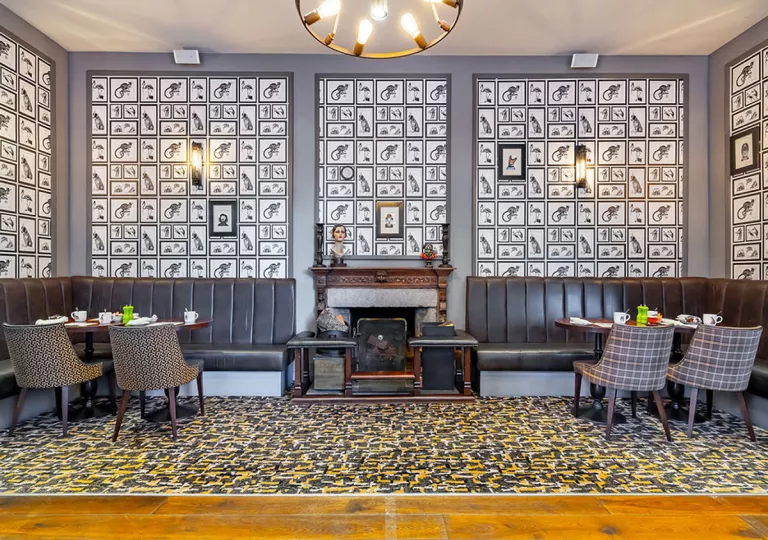 Dining area with art pieces on the wall, with cushioned sofas and dining tables