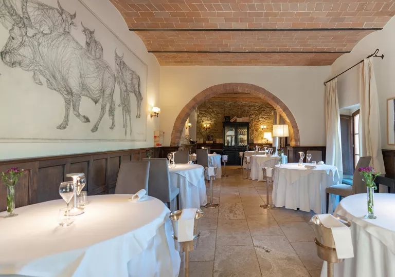 Restaurant dining room with circular tables and paintings on bulls on the wall to the left
