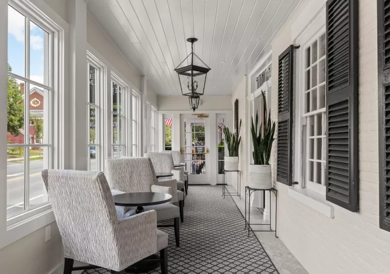 Hallway with potted plants and cushioned, white chairs