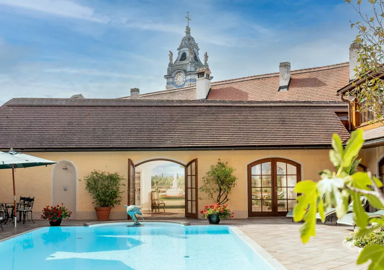 Outdoor pool with a small dolphin statue, and a clocktower in the background