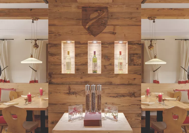 Dining hall with exposed wood walls and wine bottles on shelves