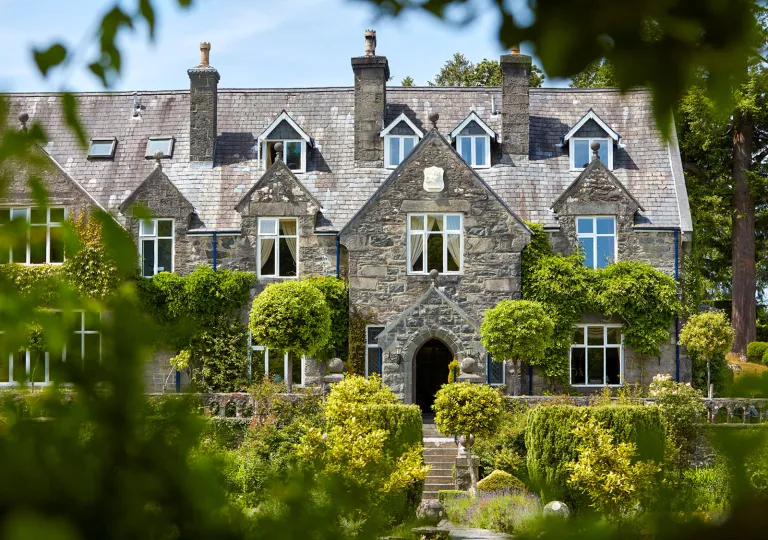 Exterior view of grey, stone building with large bushes in front