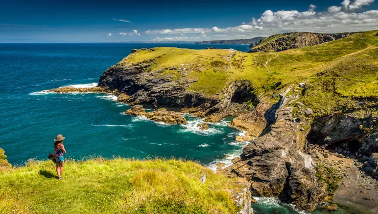 Woman standing on a grassy cliff looking out to the ocean