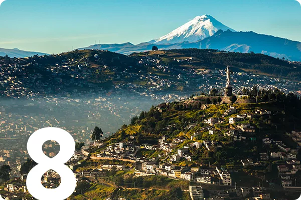 text: 8; image: aerial view of Quito with mountain in the background