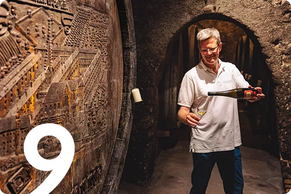 Man pouring glass of wine in cellar