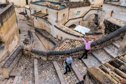 Two guests walking down stone and brick stairs, houses and buildings behind them.