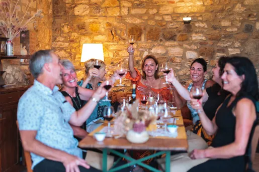 Group of guests at dinner, cheersing wine glasses.