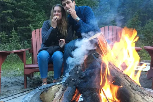 Two guests eating smores around a fire.