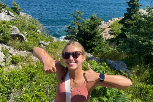 Young guest giving two thumbs up to the camera, ocean in background.
