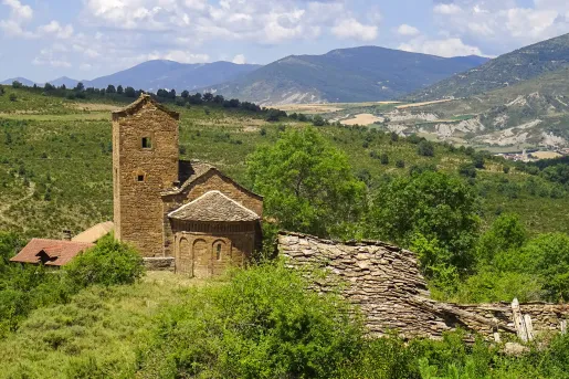 Shot of old stone building in countryside, hilly vista in distance.