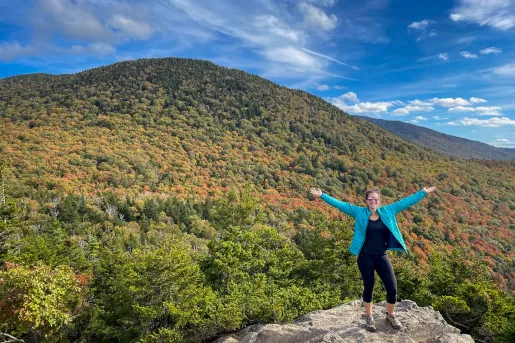 Guest gesturing to vast forest landscape, arms outstretched. 