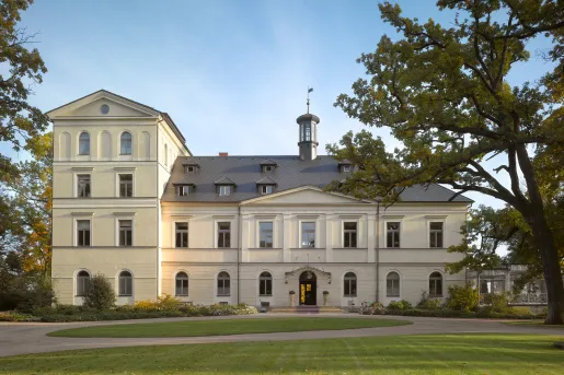 Exterior view of a yellow building, with a large grass area in front