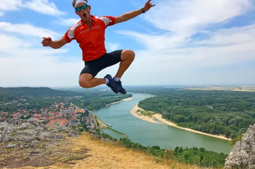 Man jumping up on a cliffside with a river in the distance