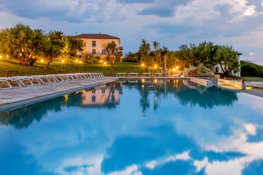 Outdoor pool with illuminated lights and large trees surrounding