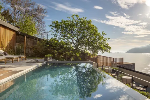Outdoor infinity pool overlooking a lake to the right