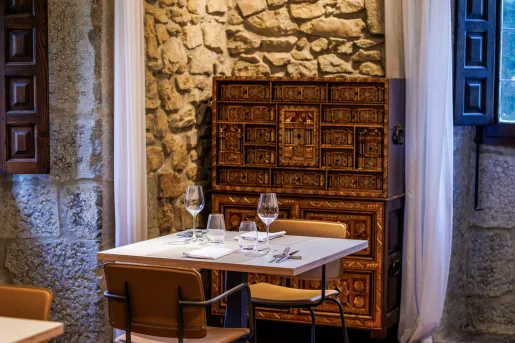 Stone-walled dining room with multiple chairs and tables, with wine glasses on each table