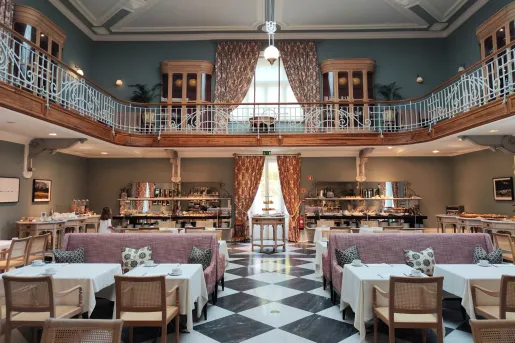 Large, two story foyer with tables on the ground floor and a balcony on the second floor