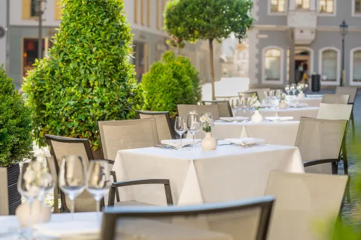 Outdoor dining area with white table cloths and wine glasses on each table