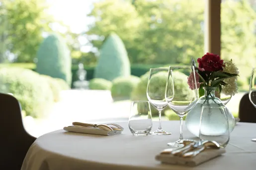 Dining table with a vase with flowers in the center, and 3 empty glasses of wine