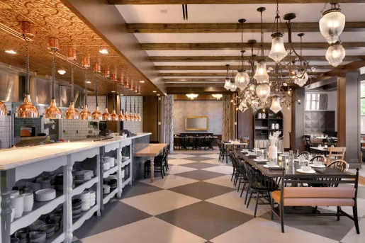 Dining hall with large light fixtures and a counter on the left full of black and white plates