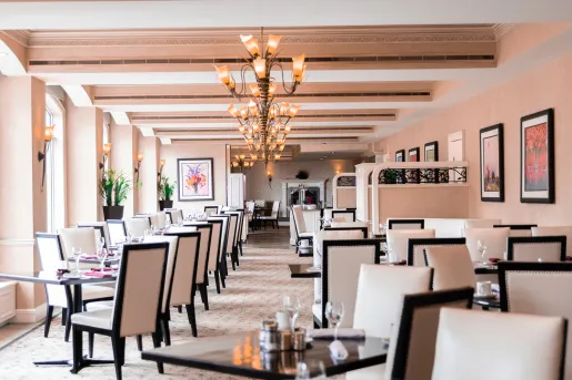 Indoor dining area with white and black cushioned chairs around square dining tables
