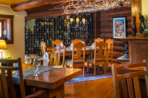 Dining room with wooden tables and chairs next to a large wine cellar