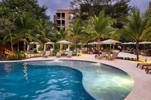 Outdoor pool with white chairs with a hotel in the background