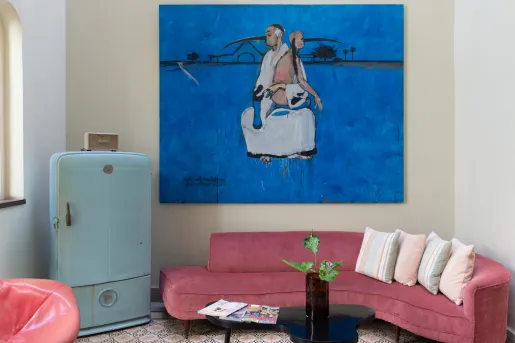 room with red couch, blue fridge, and large blue painting