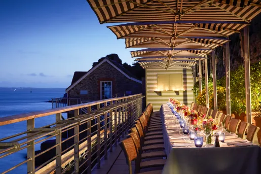 Large balcony with a long dining table with flowers and wine glasses
