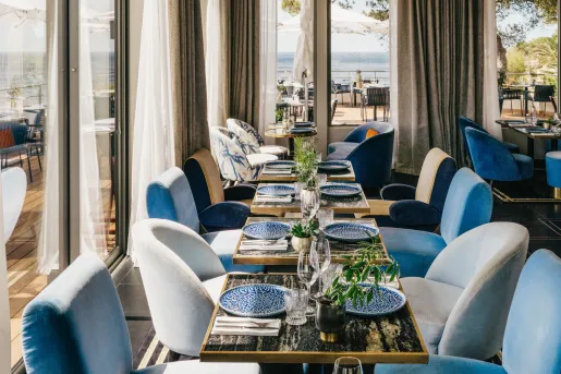 Indoor dining area with white and blue cushioned seating and large curtains