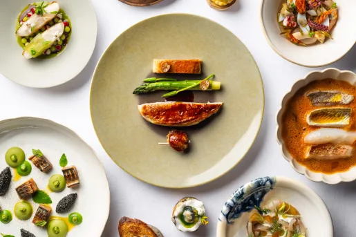 4 plates full of fancy arranges of seafood, soup, and small bites