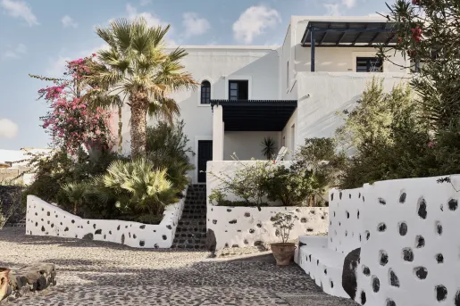 Exterior view of a white building with black accents, with a stone pathway