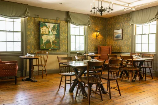 Indoor dining area with wooden tables and chairs, with large art pieces on the wall