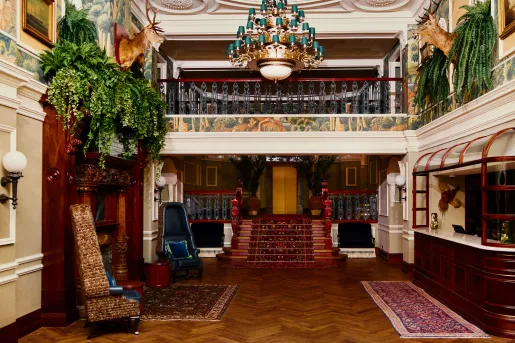 Hotel lobby with antique rugs on the floor and a small bridge walkway on the second floor