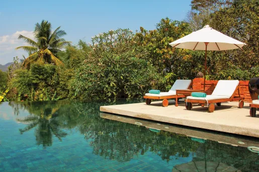 lounge chairs next to a body of water