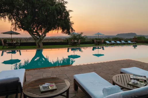 Outdoor seating around an outdoor pool, looking out towards the sunset