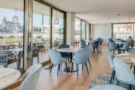 Indoor dining area with wooden tables and gray, cushioned chairs
