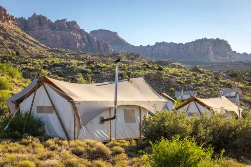 Large, luxury hut tents in the middle of a valley with canyons in the background