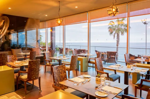 Indoor dining area with a balcony overlooking the ocean