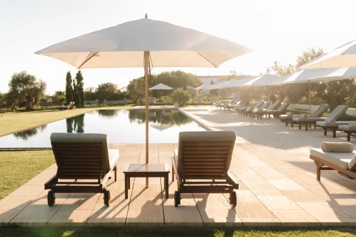lounge chairs under umbrella by the pool