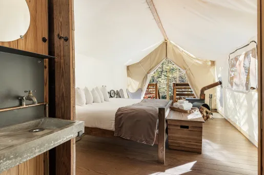 Indoor view of a hite hut, with a stone sink and a white bed