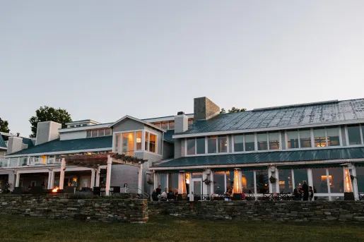 Exterior view of green and white building with an outdoor, stone patio