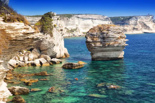 Jagged cliffs on the edge of an ocean, with a red kayak floating