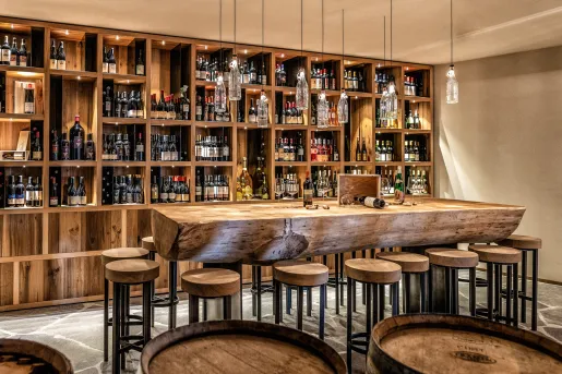 Wine cabinet behind a large table and stools made of tree stumps