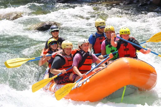 Group of men and women on an orange, inflatable raft in a river