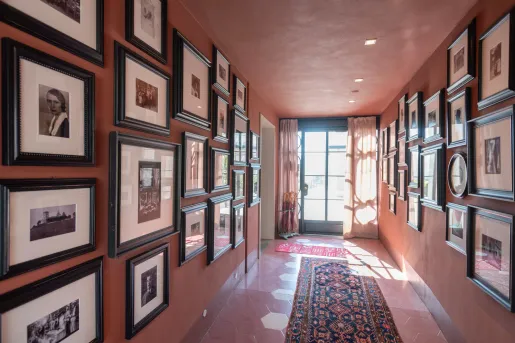 Hallway with a patterned rug and portraits on the wall